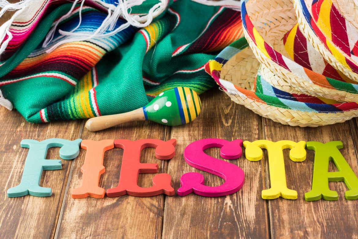 Close up of fiesta table with colorful wooden fiesta maracas, sombreros and traditional table runner.