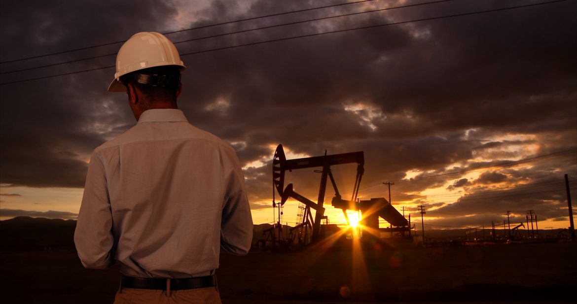 Engineer wearing hard hat helmet checking oil derrick field