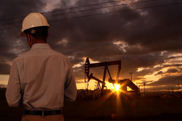 Engineer wearing hard hat helmet checking oil derrick field