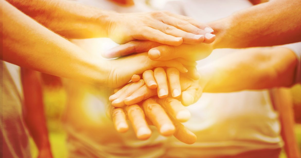 Happy volunteer family putting their hands together