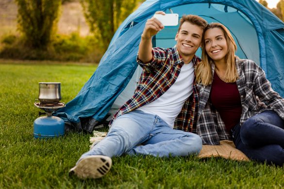 Shot of a happy couple camping on the nature and making a selfie