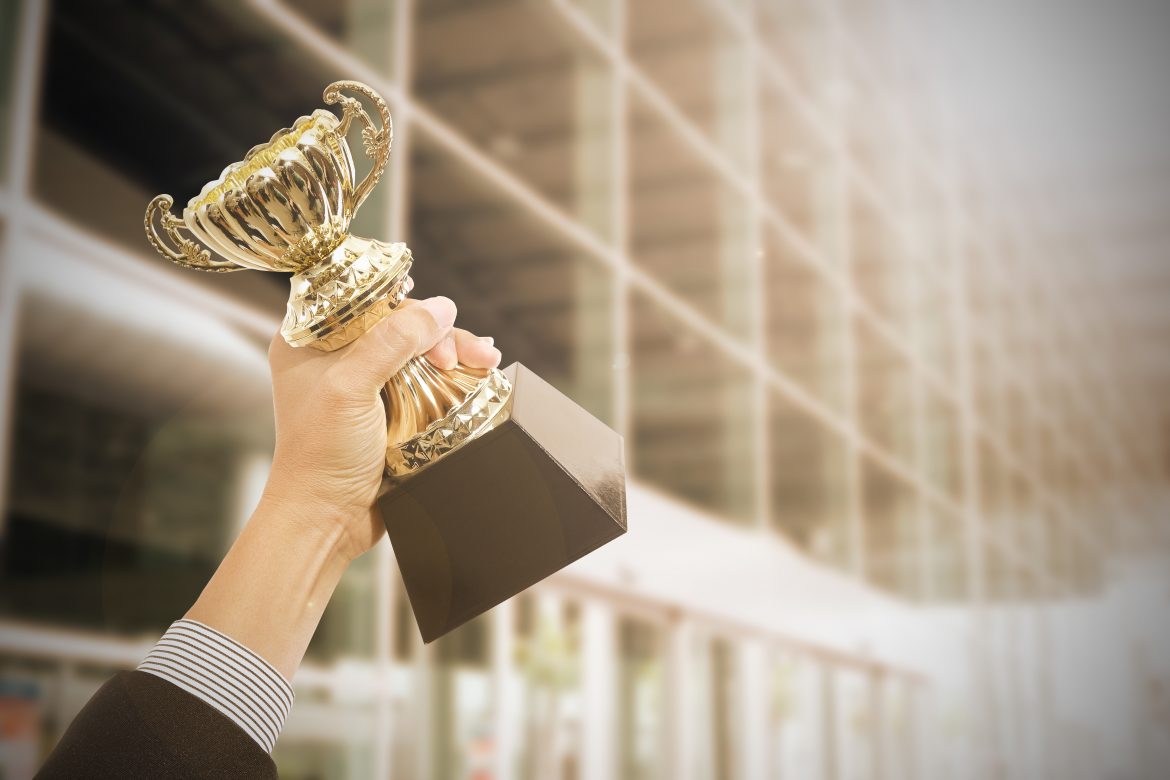 Holding Trophy awards after successful with his business.