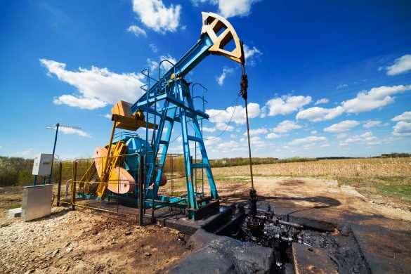 Landscape with oil pump under blue sky with clouds in a sunny day